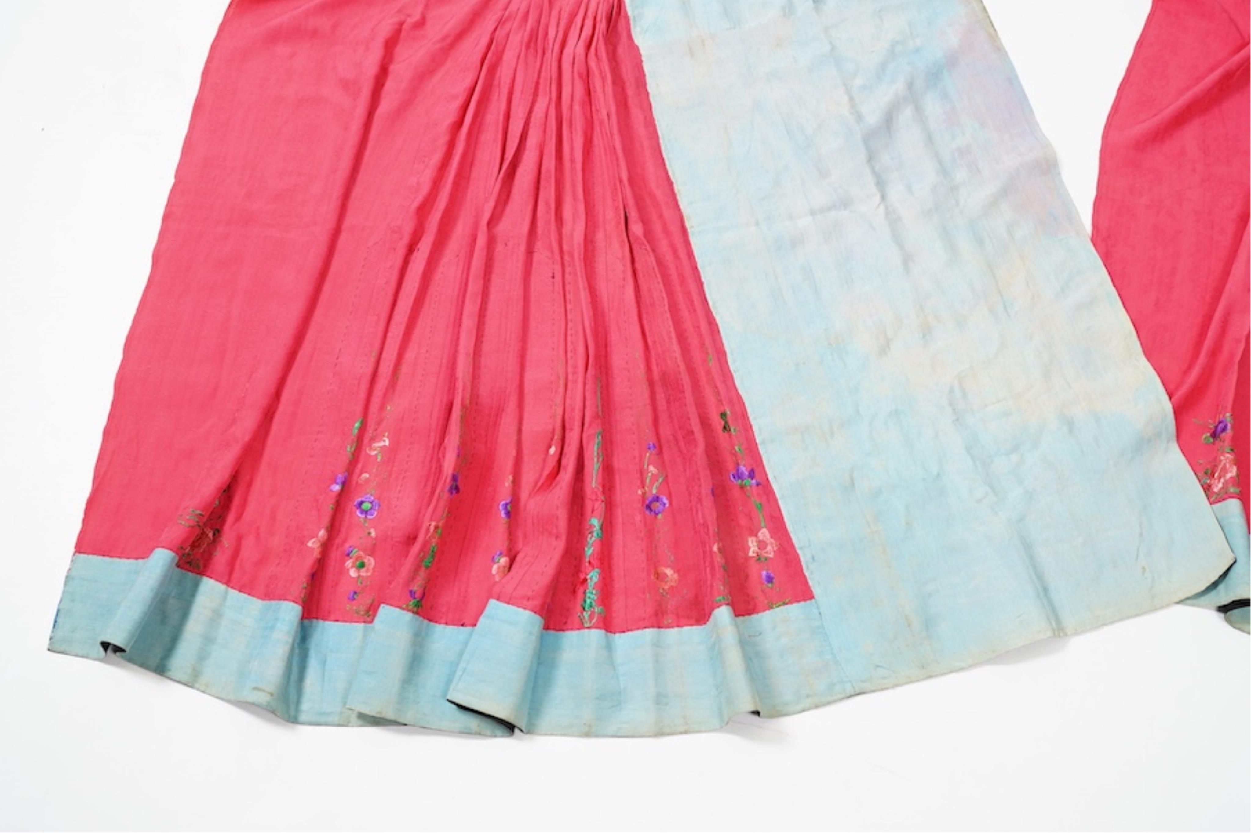 Two late 19th early 20th century Chinese wedding skirts. Made with pink silk damask, embroidered with large decorative silk floral and butterfly front panels bordered by blue embroidered black silk borders between pleats